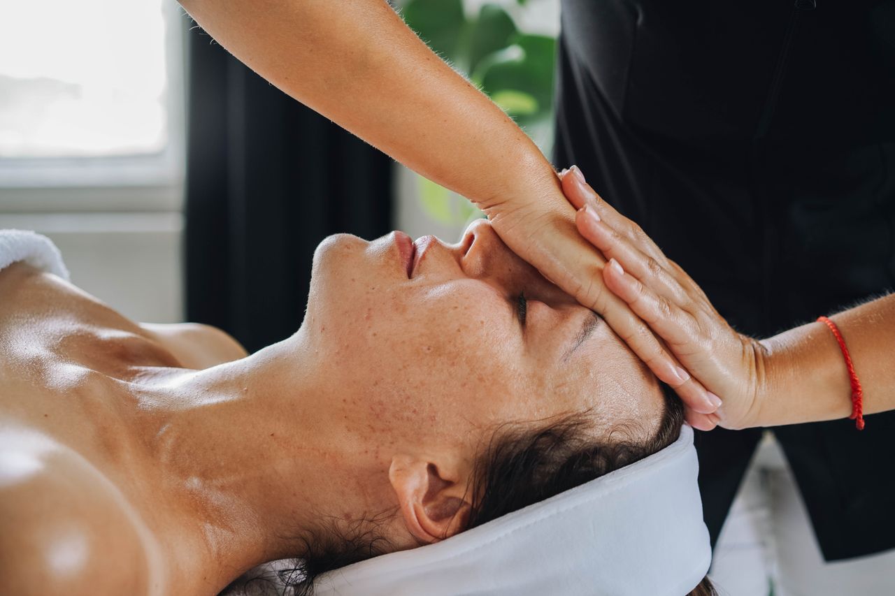 about-01 Woman receiving a calming face massage in a peaceful spa environment.